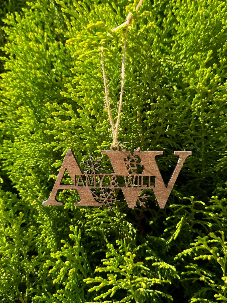 Wooden ornament with 'Amy & Will' on a wooden surface with greenery