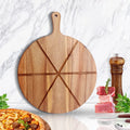 Wooden pizza peel with cutting board design on a marble surface with food items.