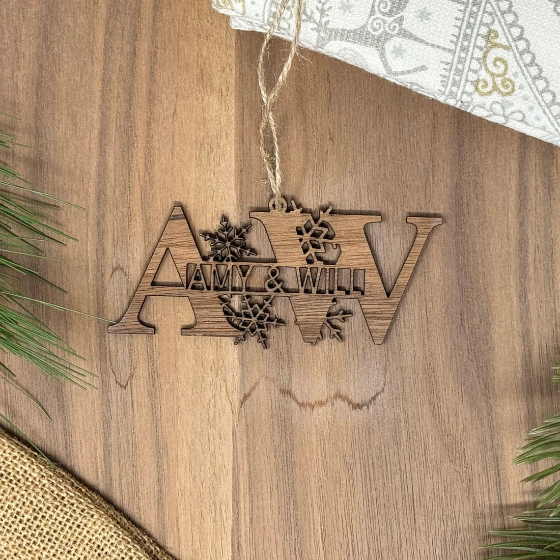 Wooden ornament with 'Amy & Will' on a wooden surface with greenery