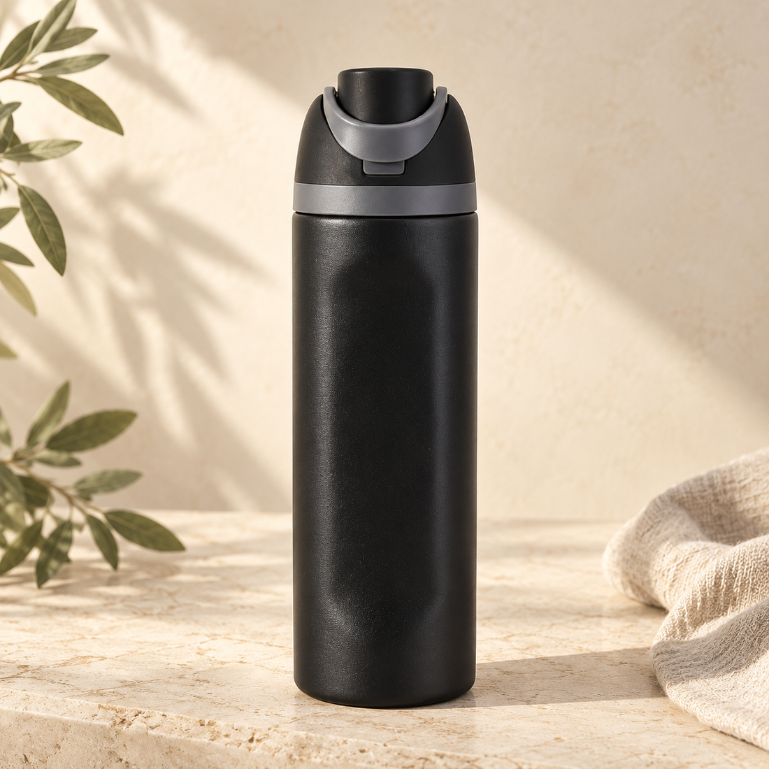 Black 24oz sports bottle with straw on warm cream stone