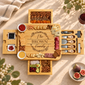 Four-drawer bamboo charcuterie board with cheese utensils, corkscrew, two white markers and serving accessories
