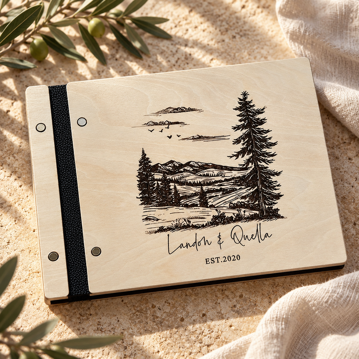 Personalized travel scrapbook with mountain engraving and black binding on a warm stone surface