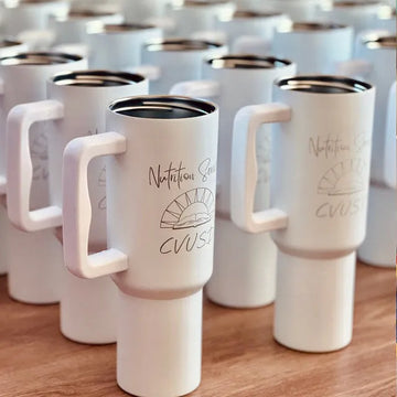 White travel mugs with handles on a wooden surface